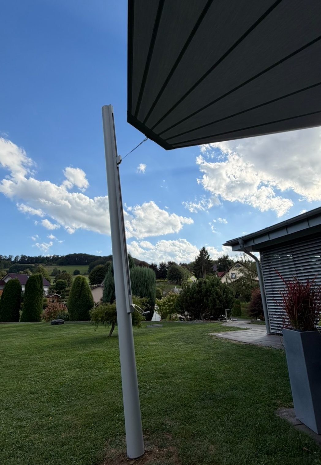 Aufrollbares Sonnensegel zwischen Hausfassade und Aluminiummasten